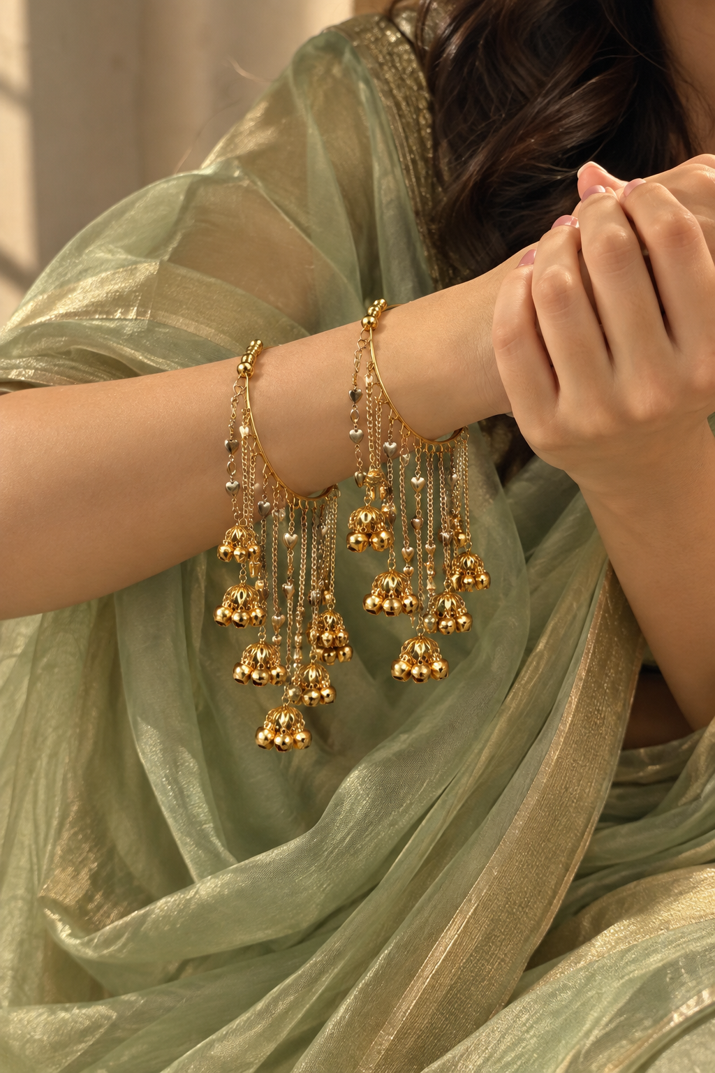 Dil Bangles in two shades of gold with dangling hearts and bells worn as a pair